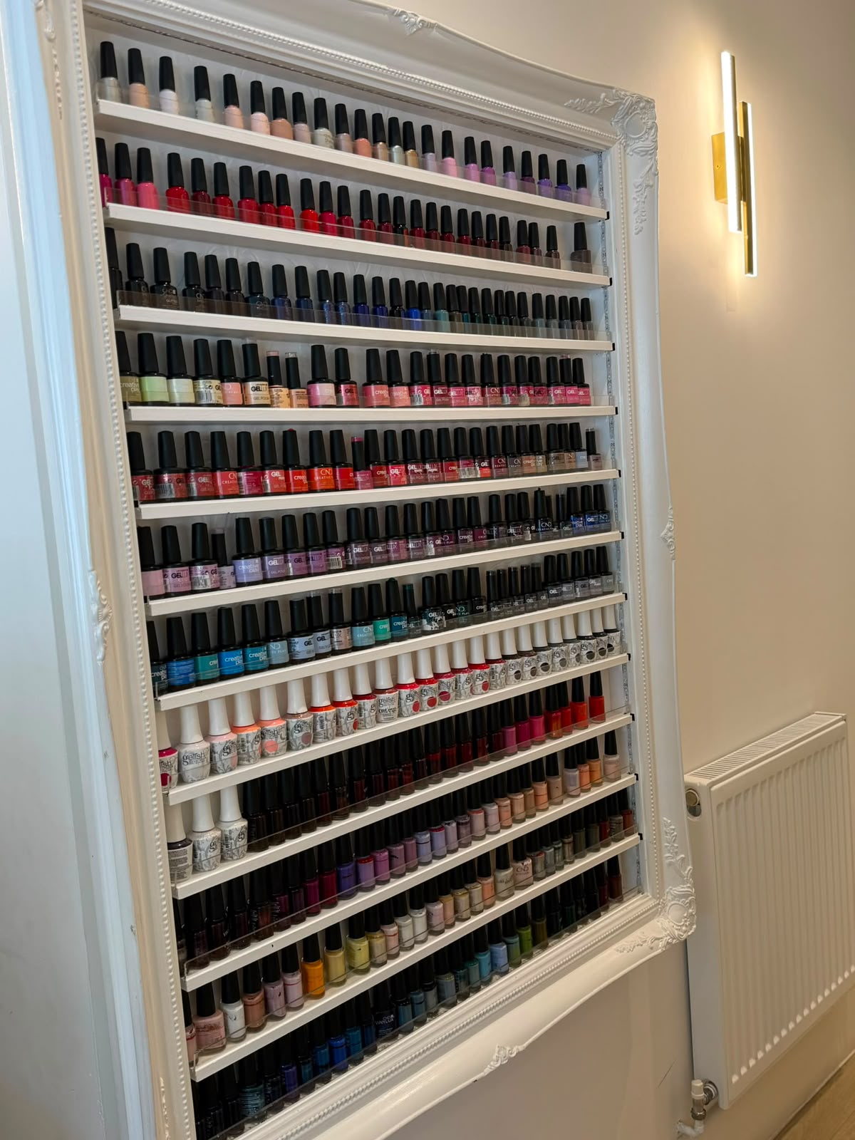 Ornate white-framed nail-polish colour wall at Precious Moments Beauty Clinic, Banstead